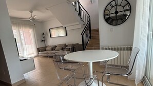 A spacious living area with a dining table and chairs, a staircase, and a large wall clock. - Modern villa with private pool on 5 star Golf Resort (Torre-Pacheco)