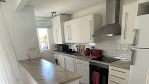 A modern kitchen with white cabinets, a central island, a built-in oven, and a window providing natural light. - Modern villa with private pool on 5 star Golf Resort (Torre-Pacheco)