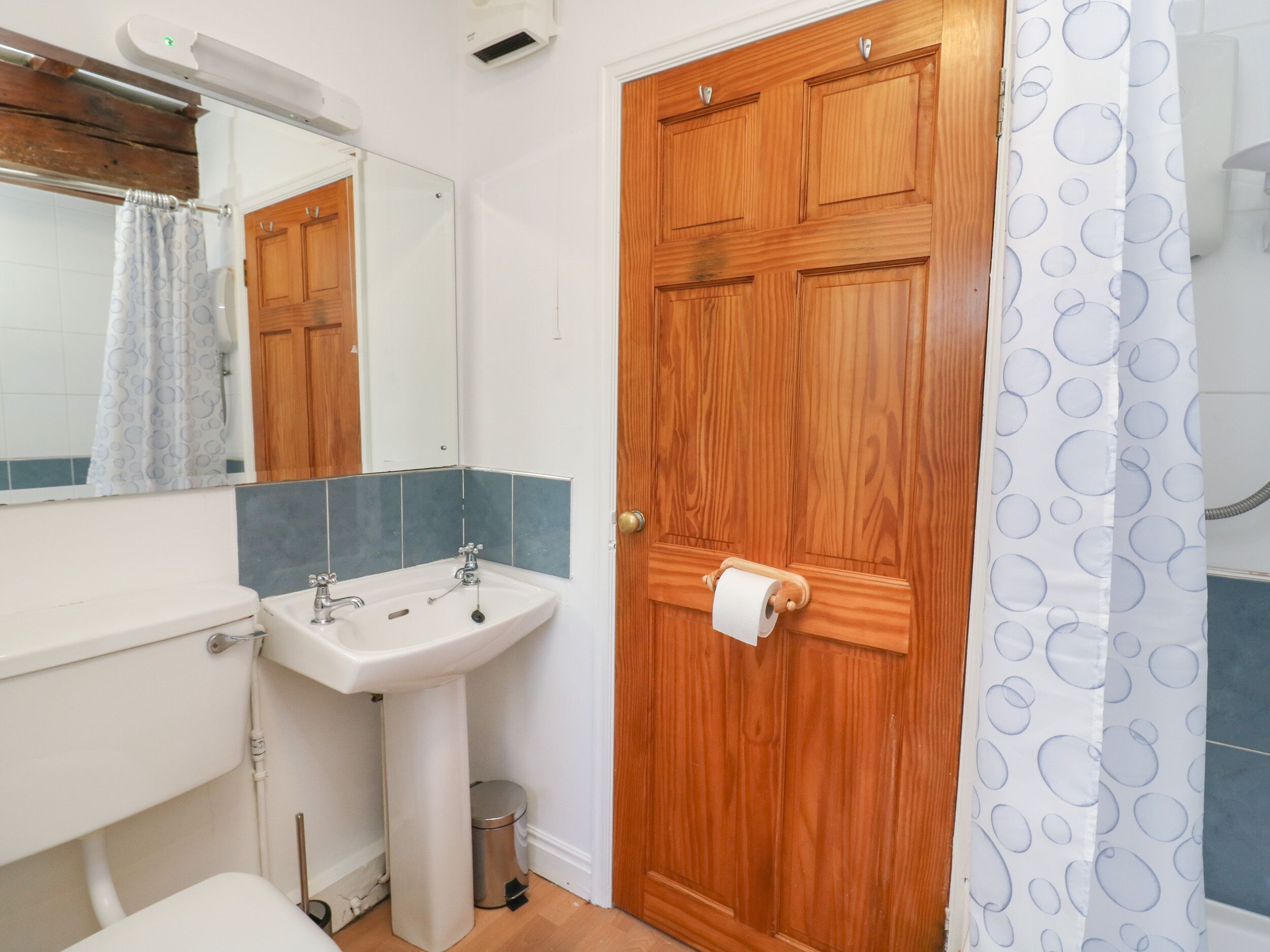 A bathroom with a wooden door, a sink, and a mirror.