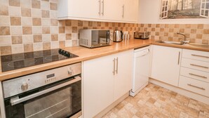 A modern kitchen with white cabinets, a built-in oven, a microwave, a toaster, and a sink. - 1 Rodgers Mews (Malton)