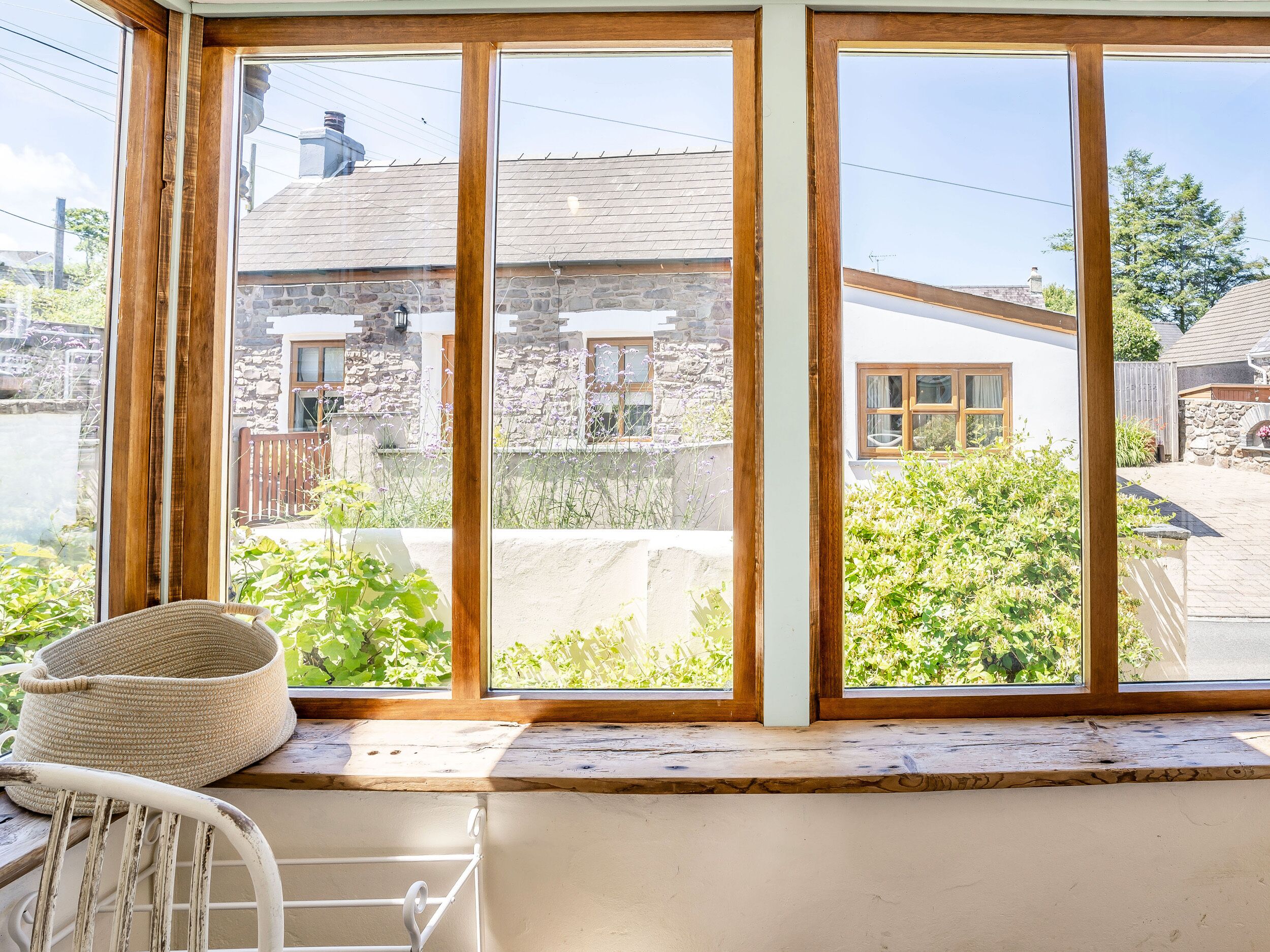 A room with a large window overlooking a stone building and greenery.