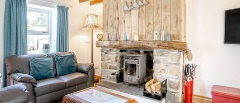 A cozy living room with a stone fireplace, leather sofa, and a coffee table.