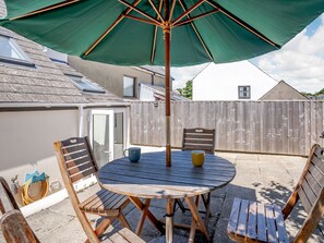 A round wooden table with chairs, a green umbrella, and a yellow cup on it. - Sea Pickle Cottage (Haverfordwest)