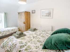 A bedroom with two single beds, a wooden wardrobe, a radiator, and a framed picture on the wall. - Sea Pickle Cottage (Haverfordwest)
