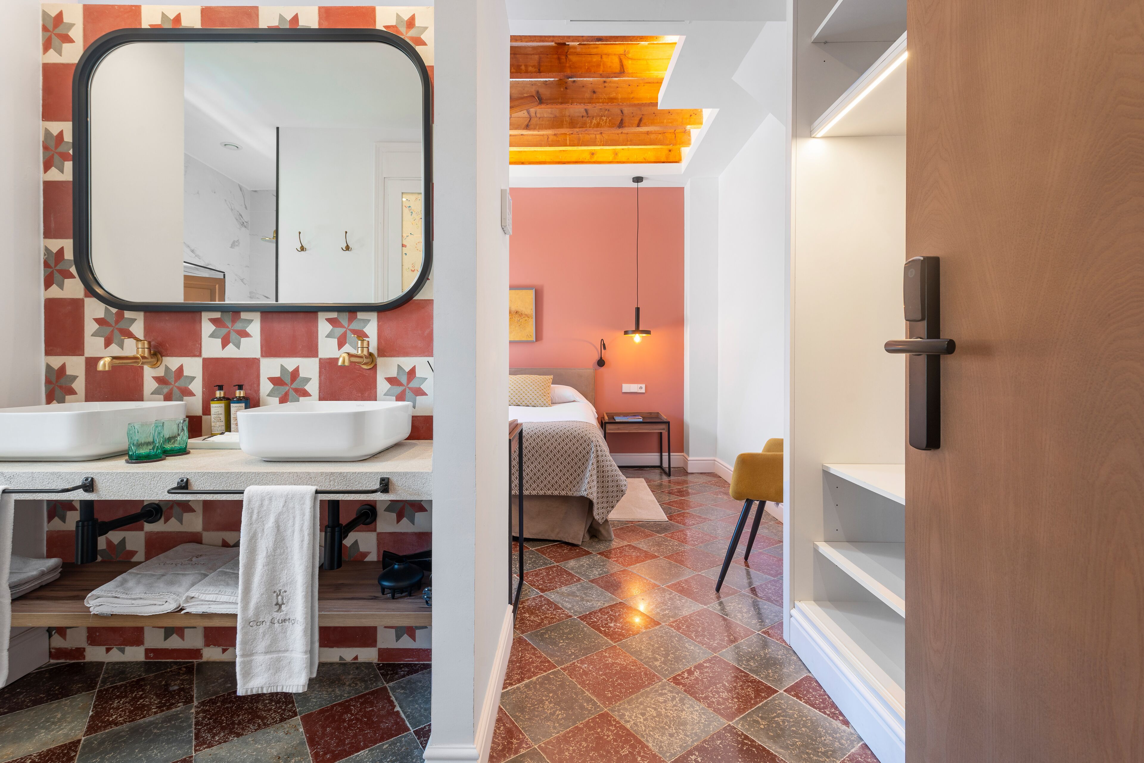 Un baño moderno con un espejo grande, dos lavamanos y una puerta de madera.