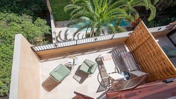 An outdoor patio with a pool, palm trees, and a wooden fence.
