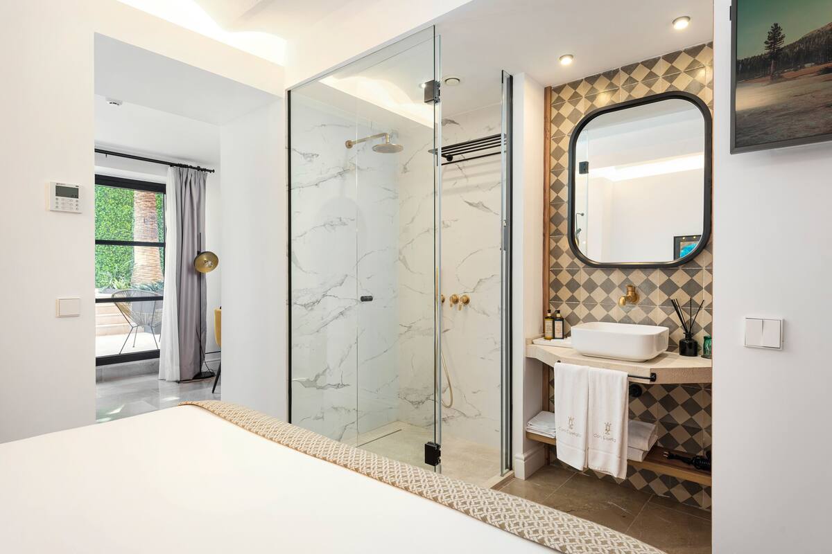 Een moderne badkamer met een douchecabine van glas, een witte wastafel en een grote spiegel.