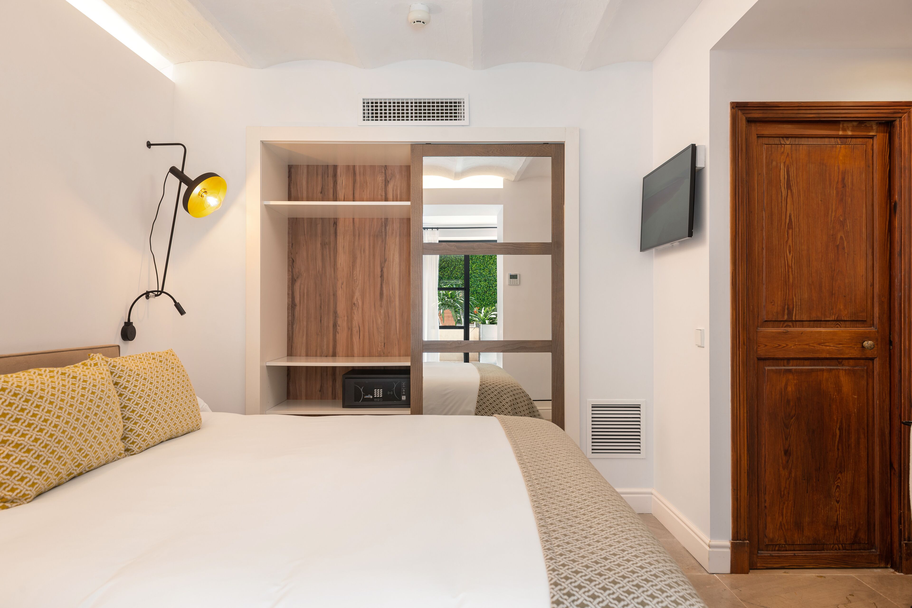 A bedroom with a bed, a wardrobe, a TV, and a door.