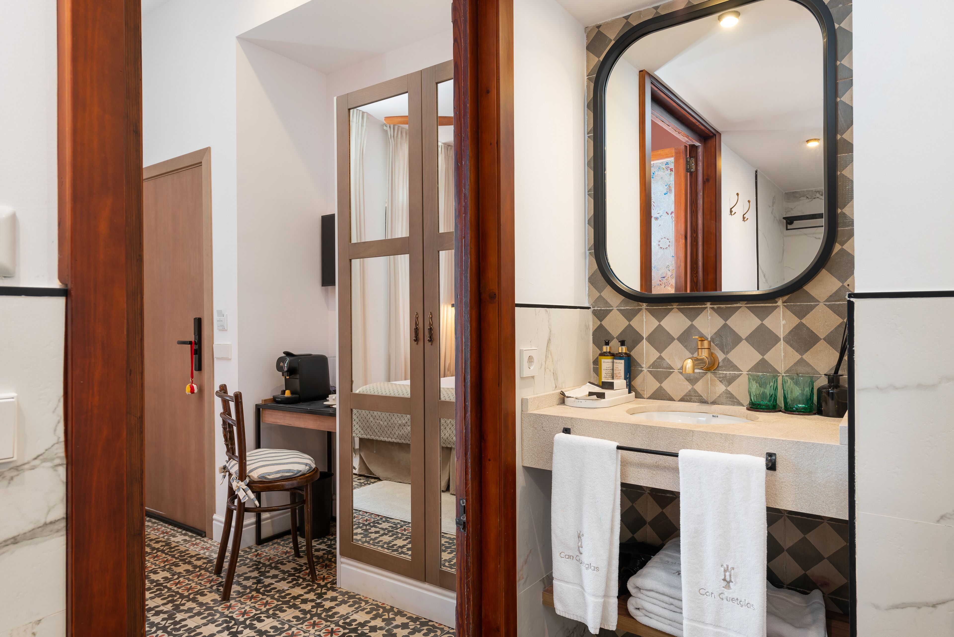 A bathroom with a wooden door, a mirror, a sink, and a towel rack.