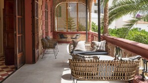 A covered outdoor seating area with wicker furniture, a ceiling fan, and a view of the surrounding landscape. - Hotel Can Quetglas - Adults Only +14 (Palma de Mallorca)