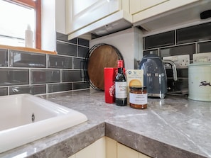 A kitchen with a white sink, a coffee maker, a jar of marmalade, a bottle of wine, and a box of biscuits. - The Stables (Preston)