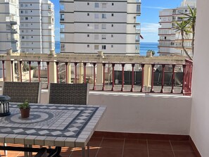 A balcony with a tiled floor, a table with chairs, and a potted plant. - Stunning penthouse apartment near the ocean with a view. Parking and Terrace (Torre del Mar)
