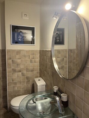 A bathroom with a glass sink, a toilet, a mirror, and a picture frame on the wall. - Stunning penthouse apartment near the ocean with a view. Parking and Terrace (Torre del Mar)