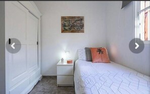 Une chambre à coucher comprenant un lit, une table de chevet, une carte murale et une armoire.