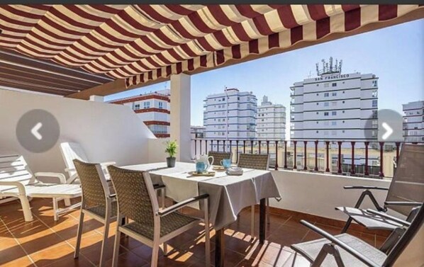 Un balcón con toldo a rayas, una mesa con sillas y vistas al horizonte de San Francisco.
