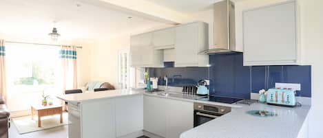 Une cuisine moderne avec des meubles blancs, un pare-feu bleu et une hotte de cuisinière en acier inoxydable.