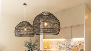A modern kitchen with a marble countertop, a dining area with a wooden table, and two hanging pendant lights. - Village Aparthotel by BOA (Porto)