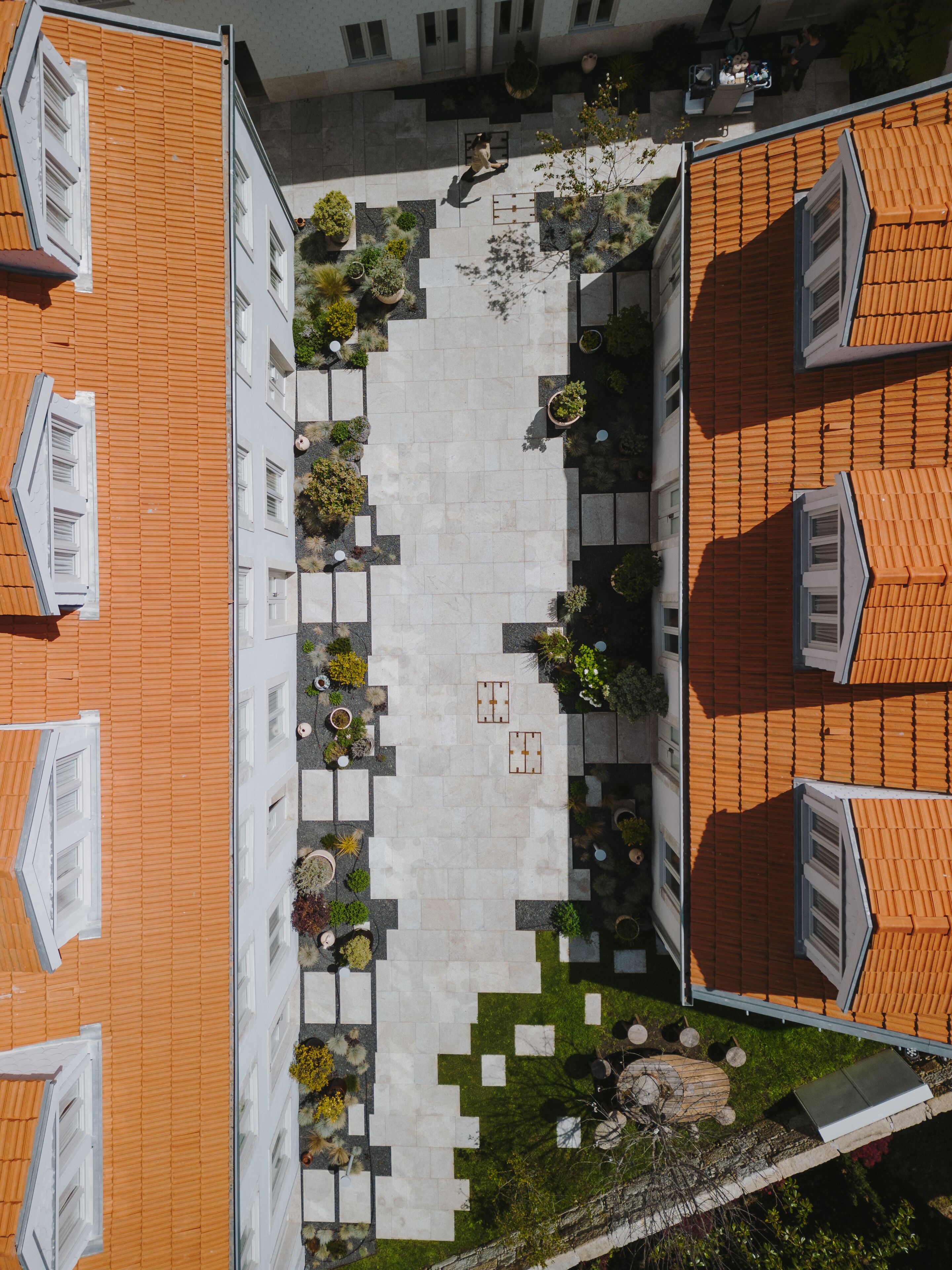 A courtyard with a central open space surrounded by buildings with orange tiled roofs and white walls.