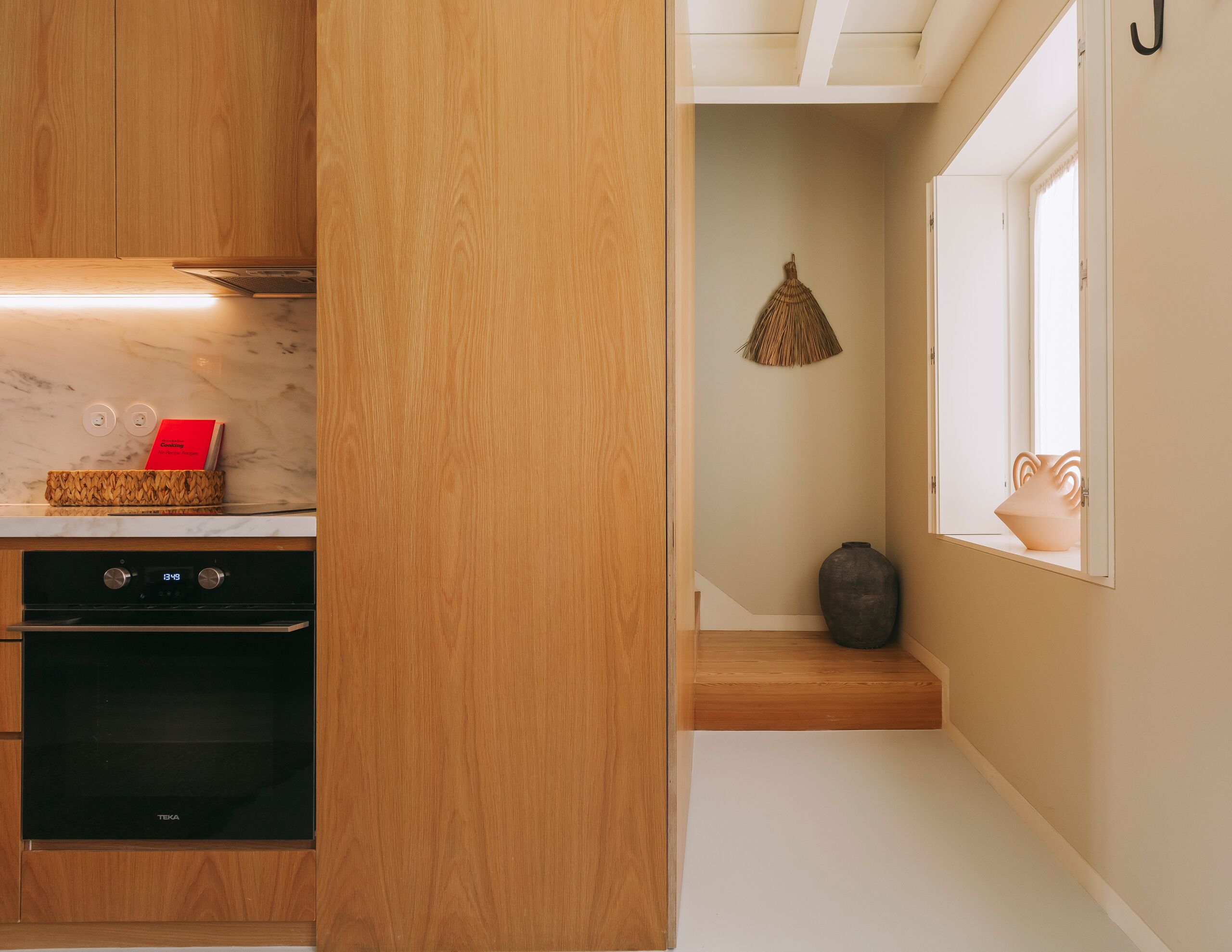 Eine moderne Küche mit Holzschränken, einem schwarzen Backofen und einer Marmorarbeitsplatte.