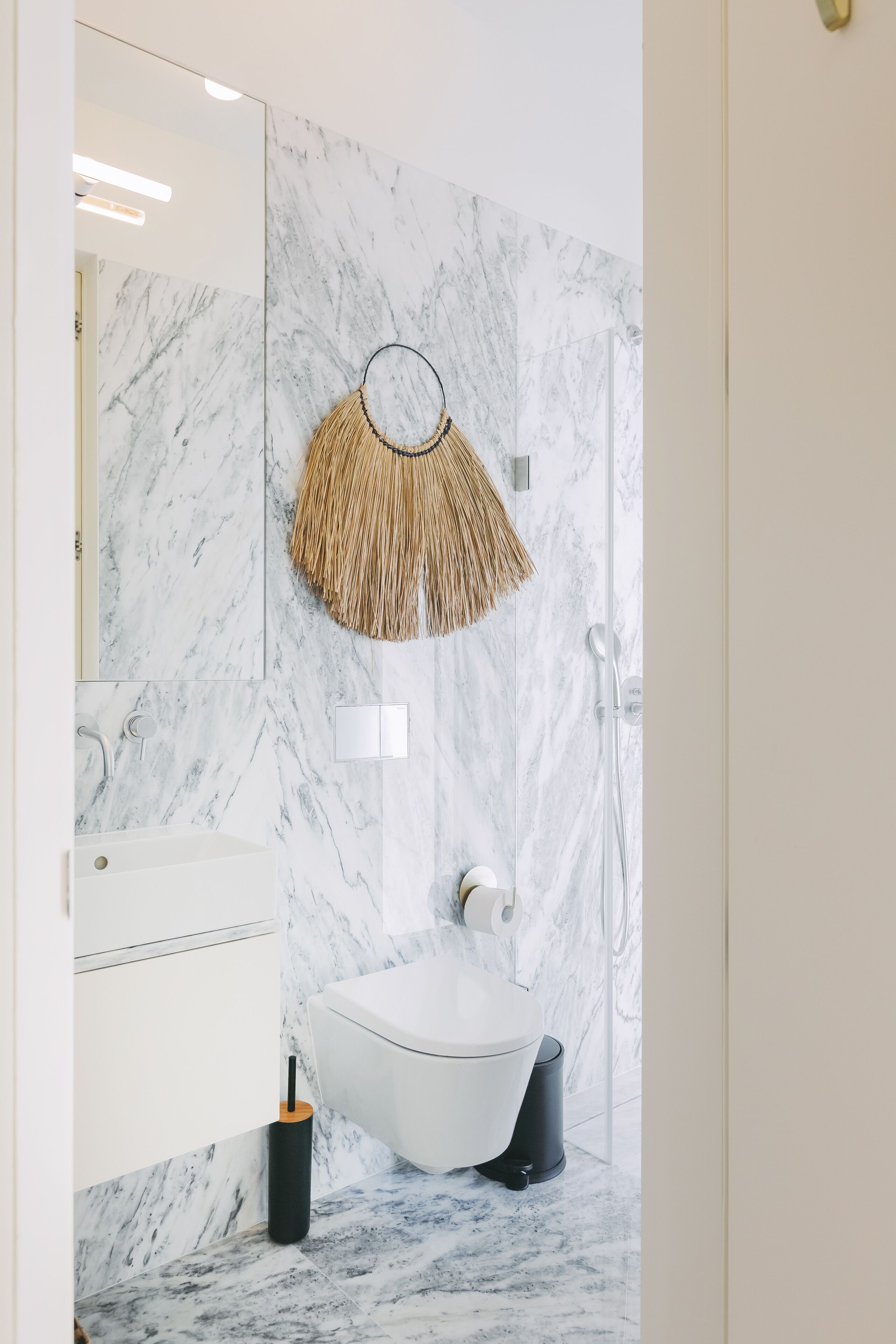 Bany amb un vàter blanc, un lavabo i una dutxa.