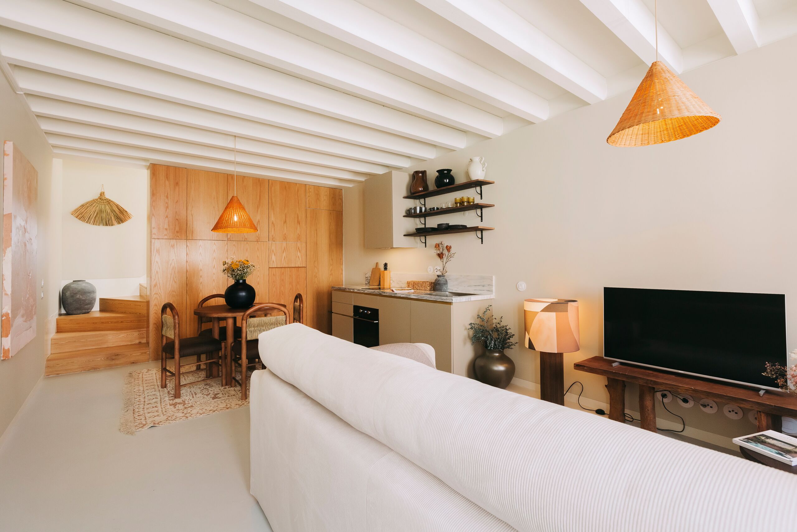 A modern living space with a kitchen area, a dining table, and a sofa.