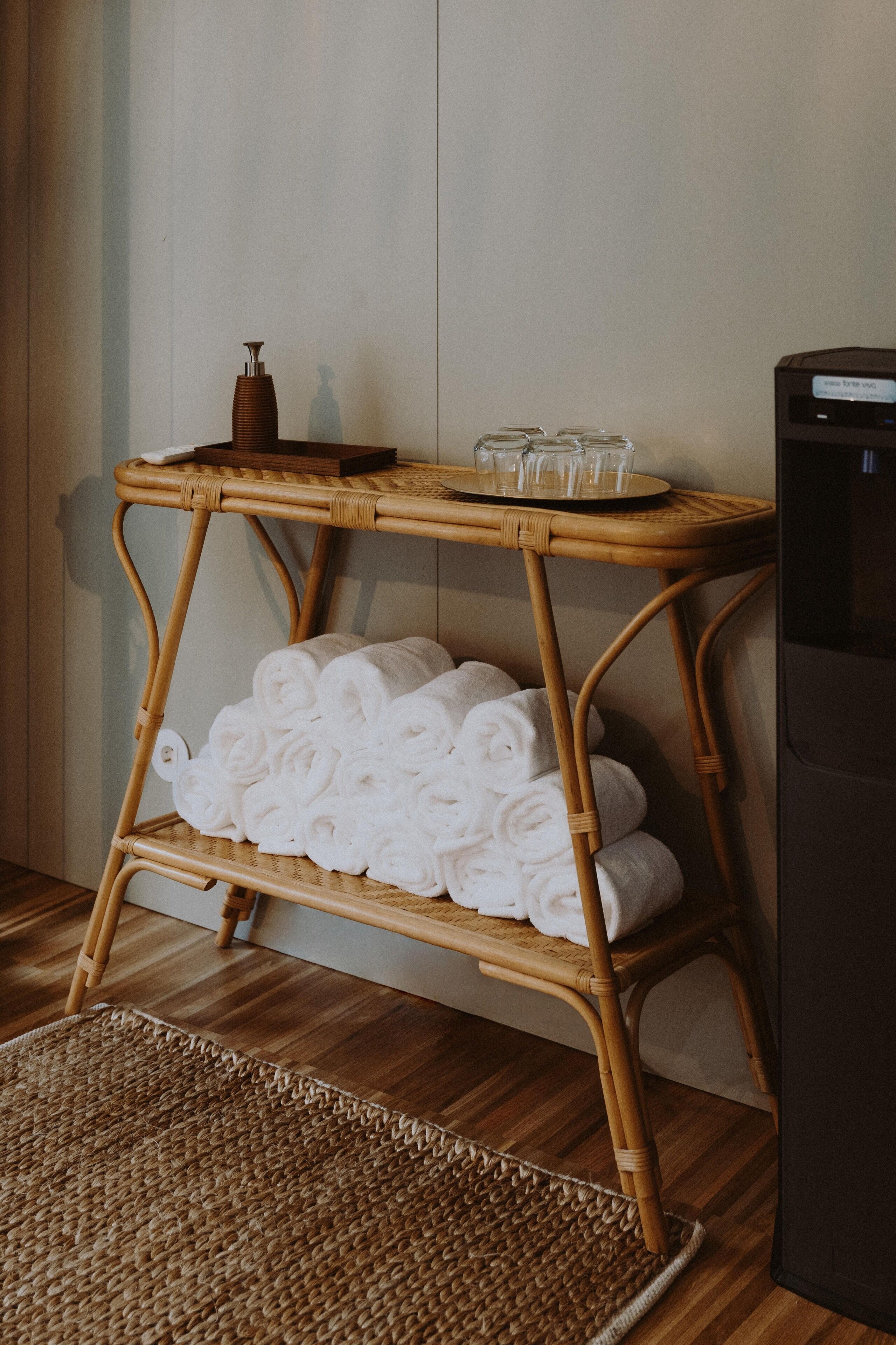 A wicker side table with towels and glasses.