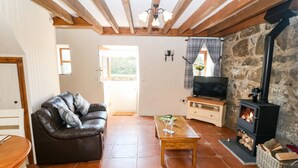Uma sala de estar acolhedora com lareira, sofá de couro, mesa de madeira e parede de pedra.