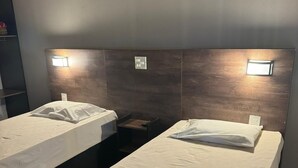 A hotel room with two single beds, a bedside table, a nightstand, and a patterned ottoman. - Hotel nova barrinha (Barrinha)