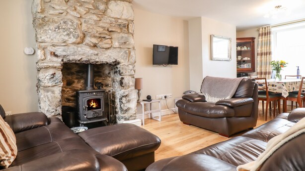 Una sala de estar acogedora con chimenea de piedra, sofás de cuero y un comedor con mesa y sillas.