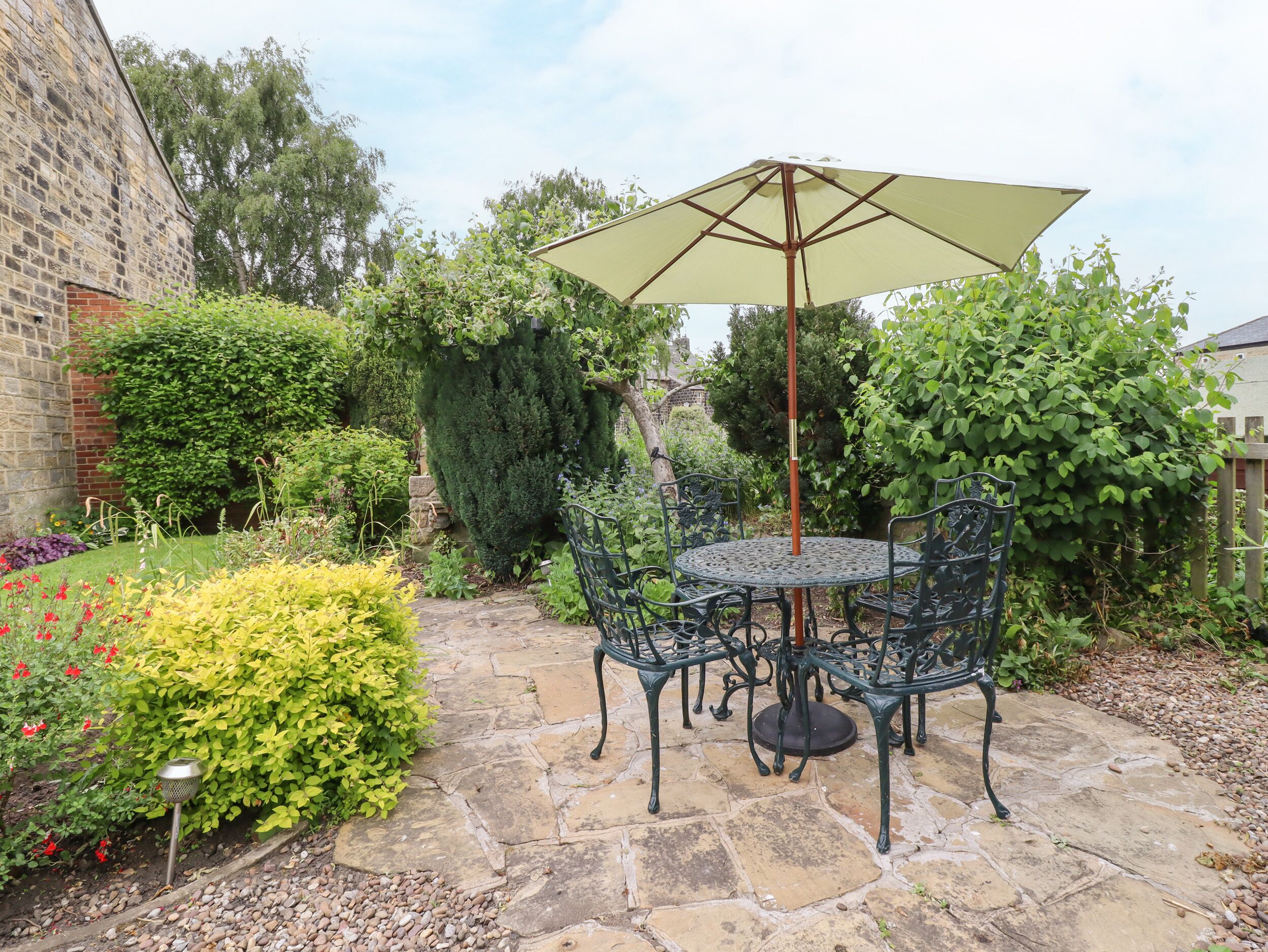 A patio with a round table and chairs, an umbrella, and a stone pathway.