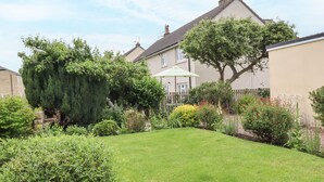 Un jardín residencial con césped, varios arbustos y un árbol.