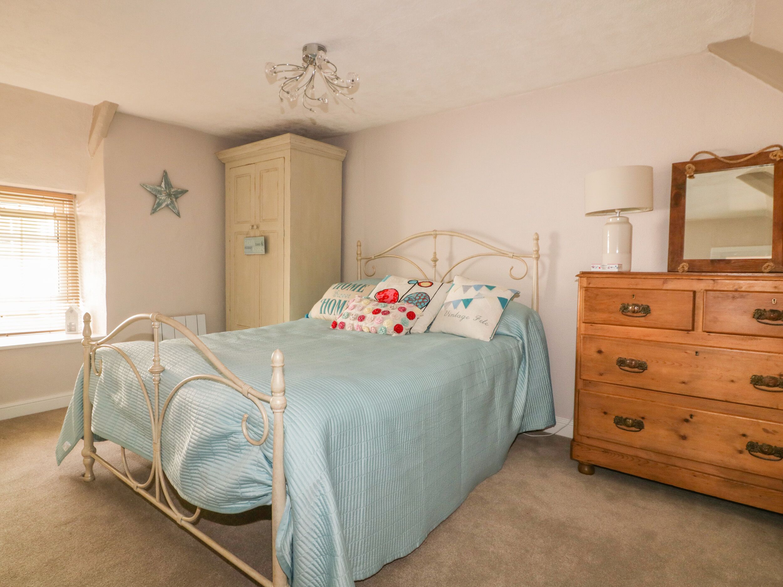 A bedroom with a bed, dresser, and wardrobe.