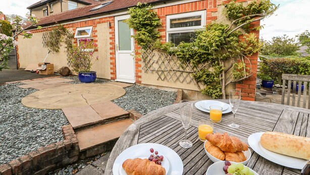 Een terras met een ontbijttafel, inclusief croissants, druiven en sap.
