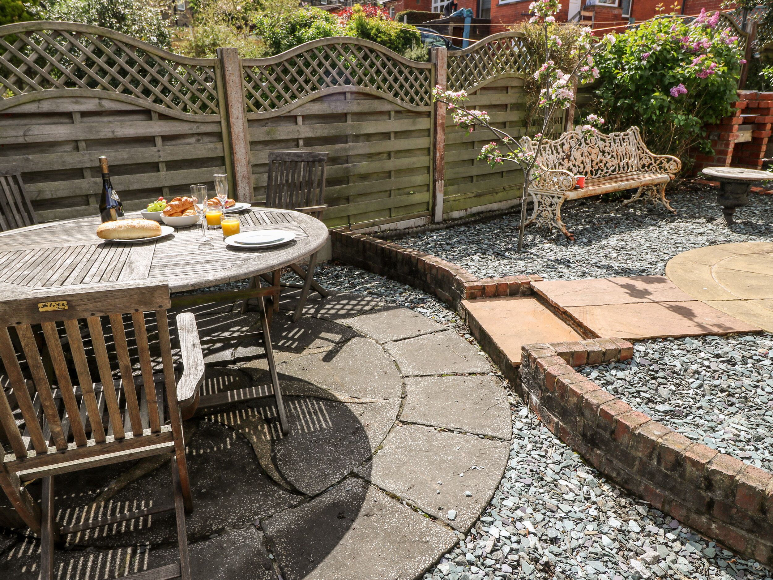An outdoor patio with a round table, chairs, and a bench.