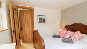 Een slaapkamer met een houten bed, wit beddengoed en een houten deur.