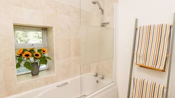 Un baño con bañera, ducha y una ventana con girasoles.
