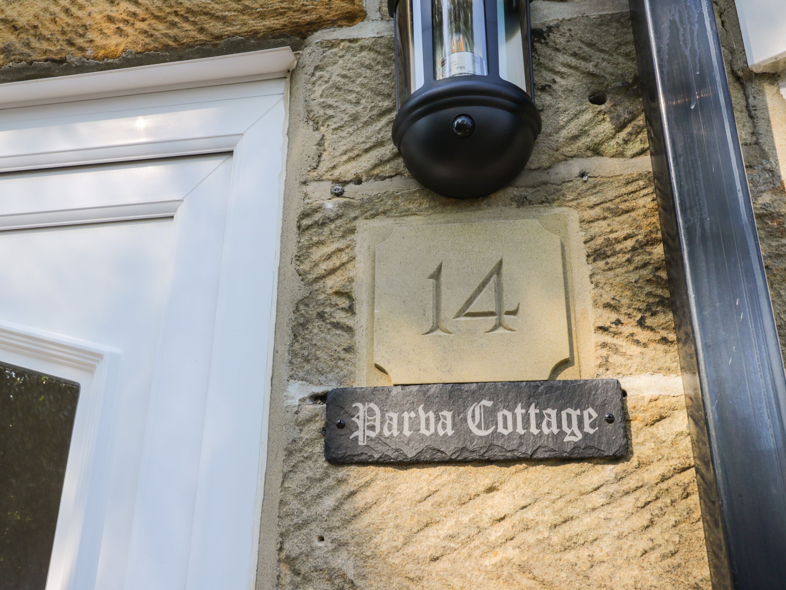 A stone wall with a number plaque '14' and a sign reading 'Parha Cottage'.