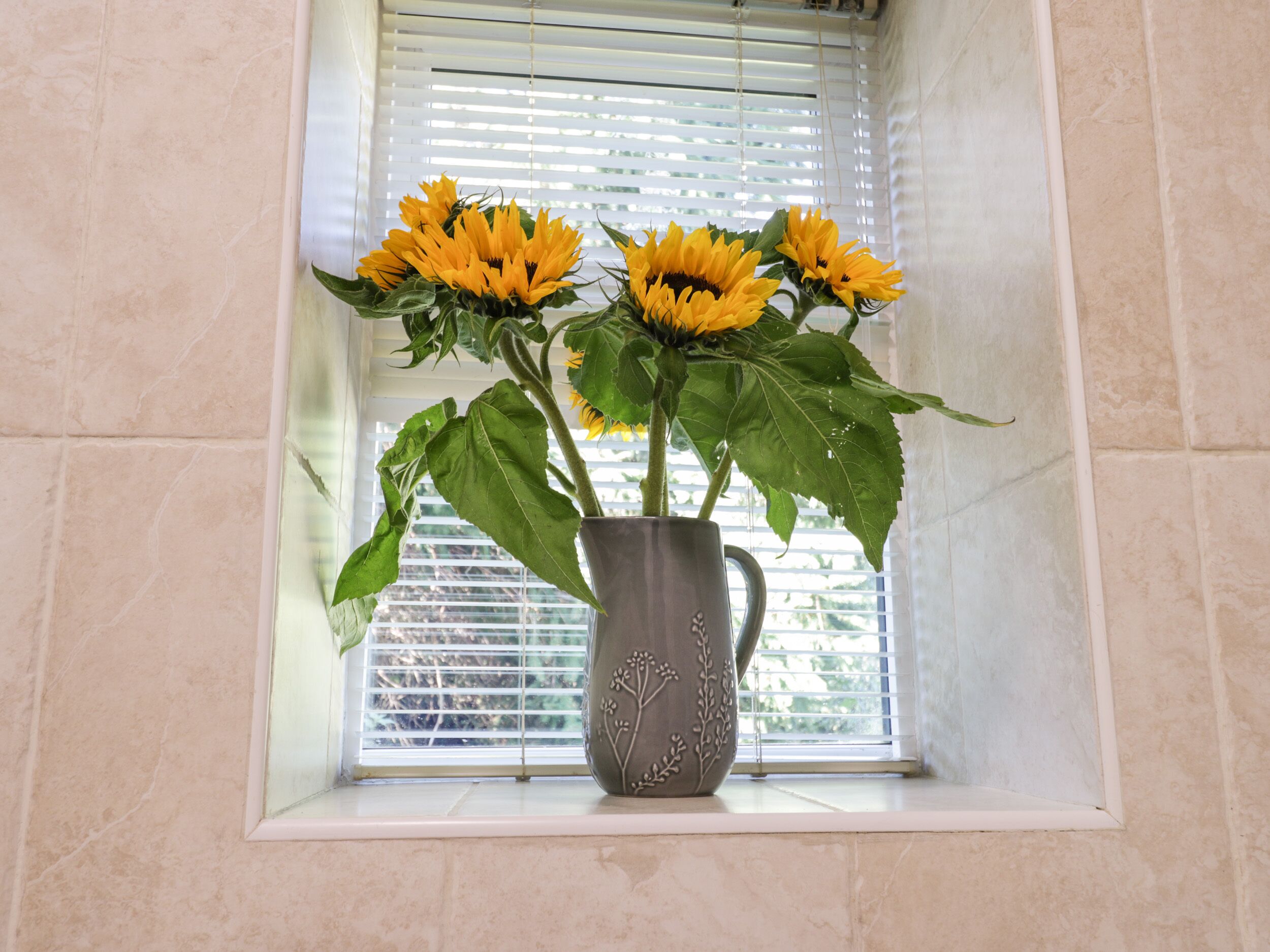 A vase with sunflowers on a windowsill.