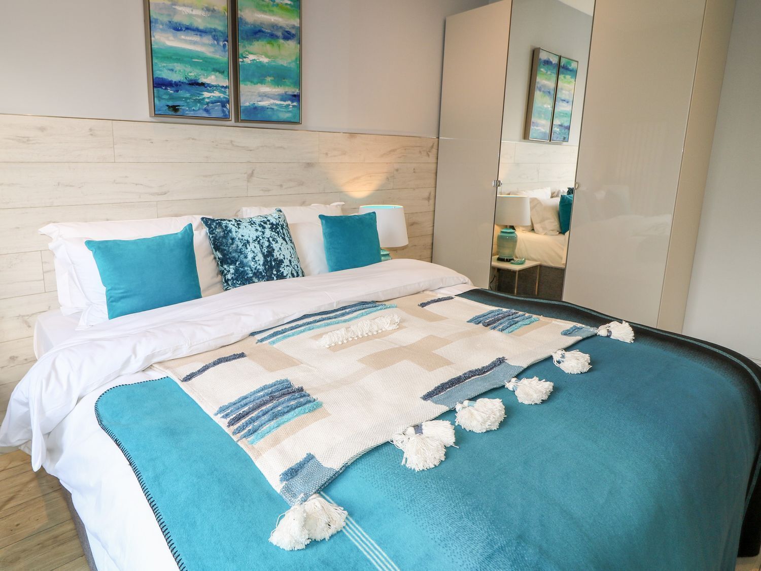 Un dormitorio moderno con cama, un espejo grande y obras de arte en la pared.