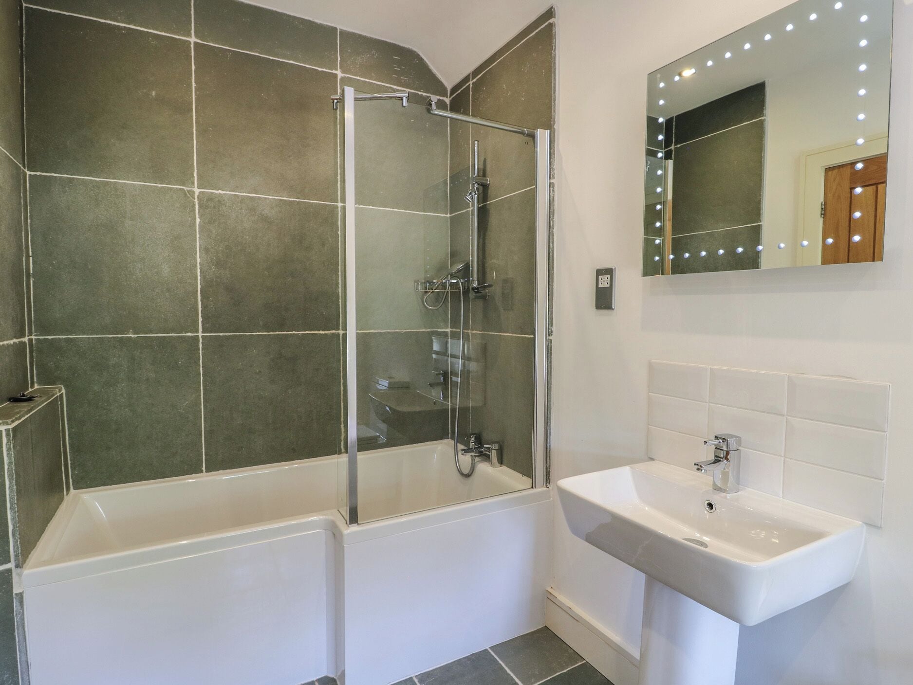 Un baño con ducha de vidrio, una bañera blanca y un lavabo con espejo.