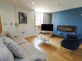 Una sala de estar con sofá, televisor, chimenea y ventana.