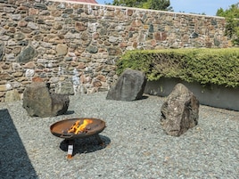 Un muro de piedra, un hogar y rocas en un jardín.