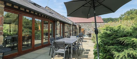 An outdoor patio with a table and chairs, a large umbrella, and a stone wall.