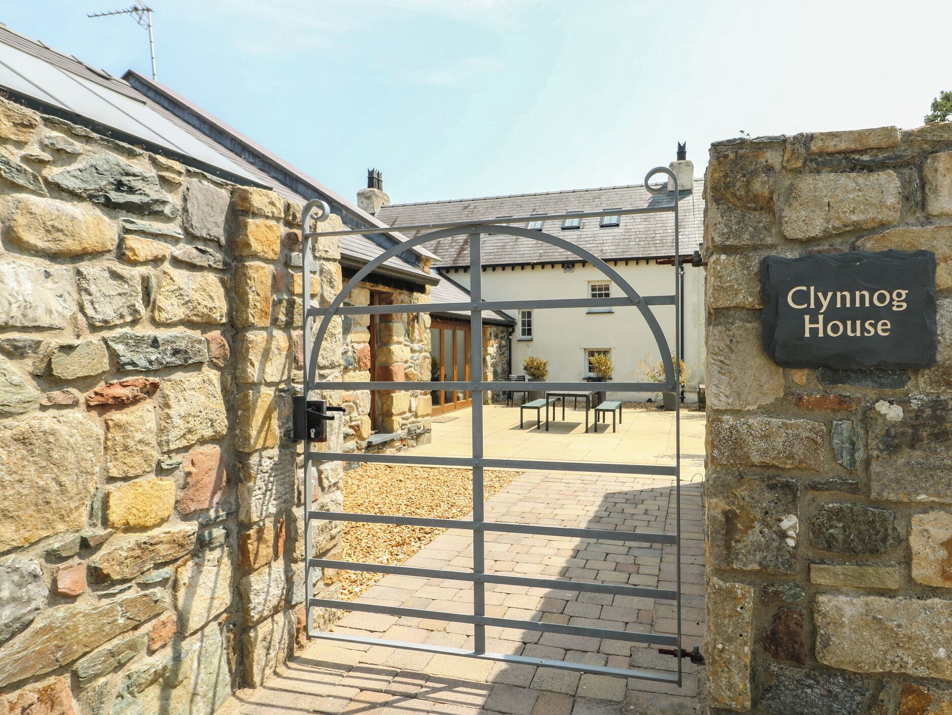 A stone gate leading to a courtyard with a sign reading 'Clynog House'.