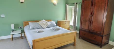 A bedroom with a wooden bed, bedside tables, a wardrobe, and two wall-mounted lights.