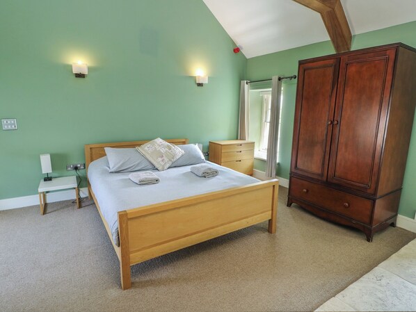 A bedroom with a wooden bed, bedside tables, a wardrobe, and two wall-mounted lights.