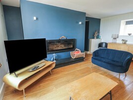 Una sala de estar moderna con televisor de pantalla plana, chimenea, sofá azul y una mesa de centro de madera.