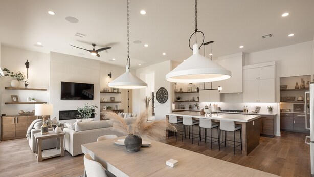 A modern kitchen with a central island, white cabinetry, and a dining area with a wooden table and chairs. - Modern 3BR Parade Home - w/Casita & Putting Green (St. George)