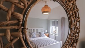 Un dormitorio con cama, mesita de noche, lámpara y ventana con cortinas.