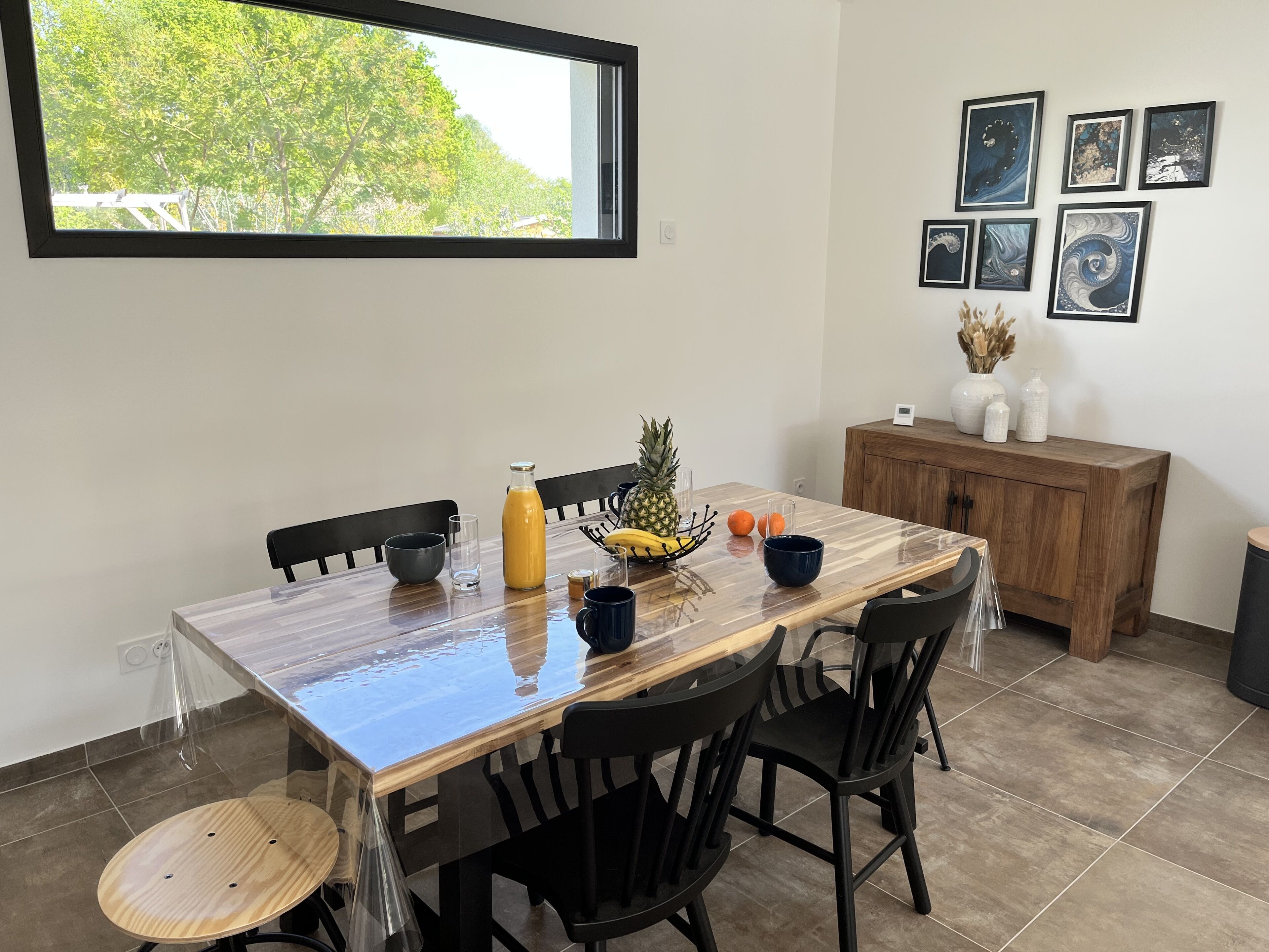 A dining area with a wooden table, chairs, and a fruit bowl.